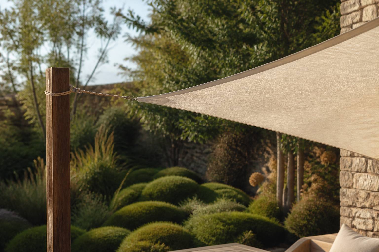 Voile d'ombrage fixée à un poteau en bois et à un mur de jardin